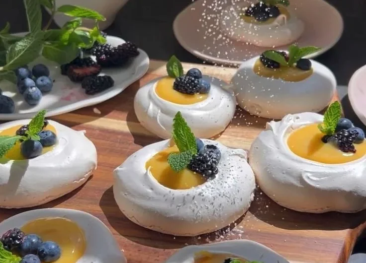 Meringues topped with bright citrus curd on a white plate