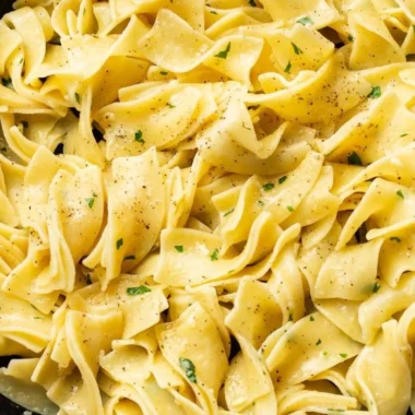 Plate of hot buttered egg noodles garnished with parsley.