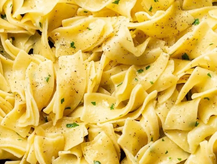 Plate of hot buttered egg noodles garnished with parsley.