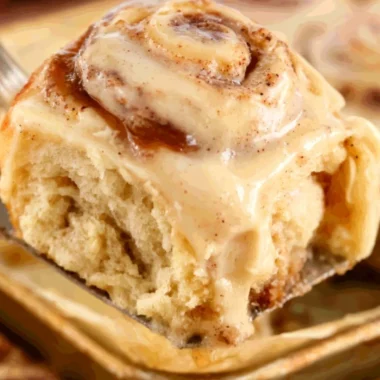 Delicious apple butter cinnamon rolls topped with icing on a rustic wooden table.