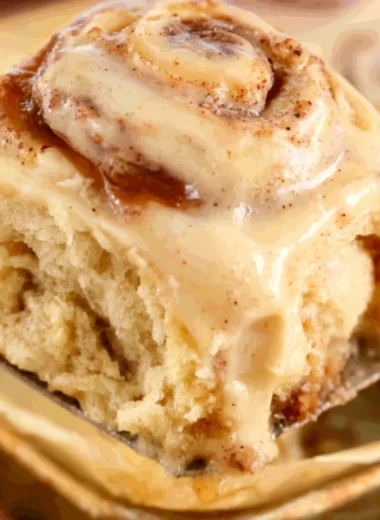 Delicious apple butter cinnamon rolls topped with icing on a rustic wooden table.