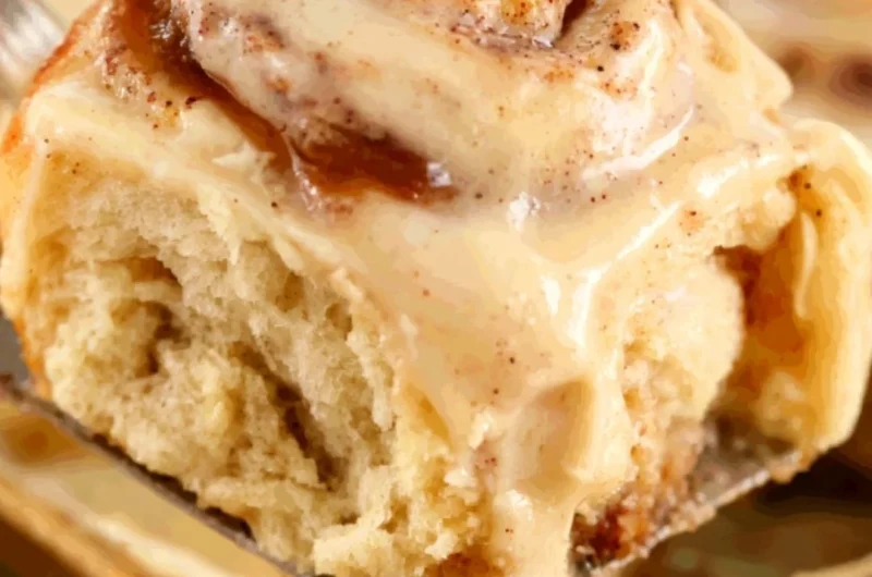 Delicious apple butter cinnamon rolls topped with icing on a rustic wooden table.