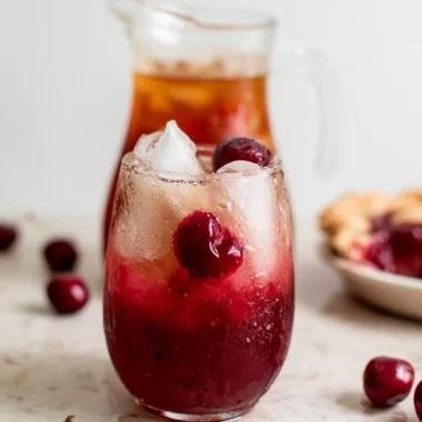 Cherry pie inspired iced tea served in a glass with fresh cherries and mint leaves.