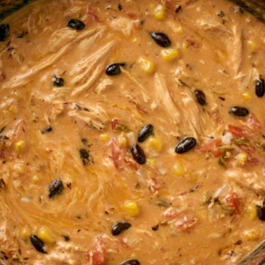 A bowl of slow cooker creamy chicken tortilla soup topped with avocado and tortilla strips.