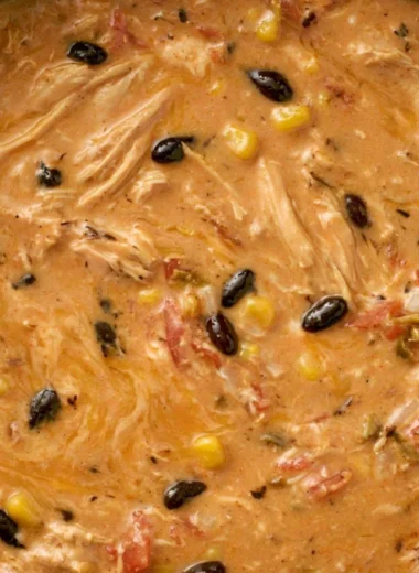 A bowl of slow cooker creamy chicken tortilla soup topped with avocado and tortilla strips.