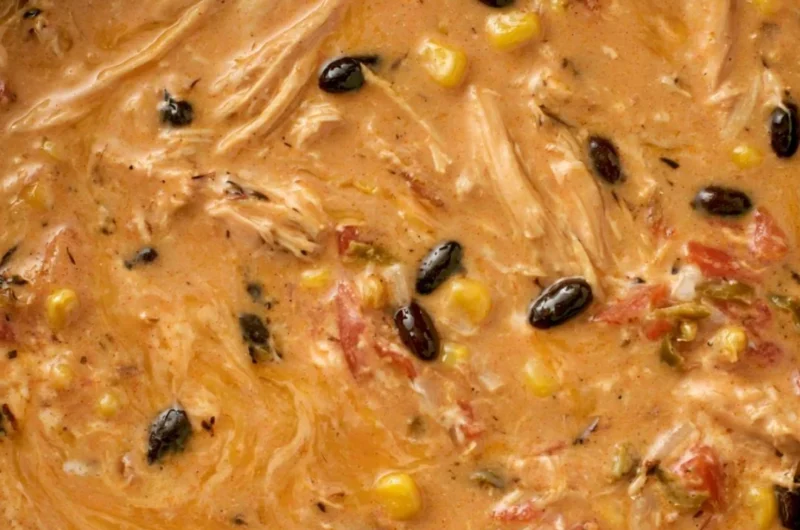 A bowl of slow cooker creamy chicken tortilla soup topped with avocado and tortilla strips.