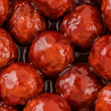 Cozy crockpot meatballs in grape jelly and BBQ sauce served in a dish